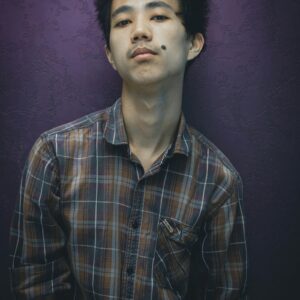 Brown and blue checked button-up shirt worn against a plum wall.