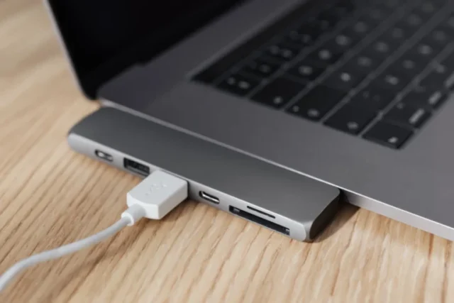 USB-C multiport adapter connected to a laptop on a wooden desk.