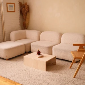 Warm living room with a cream bouclé sofa, timber lounge chair and low stone table