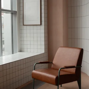 A minimalist room featuring a brown leather armchair and a framed blank canvas, ideal for modern decor inspiration.