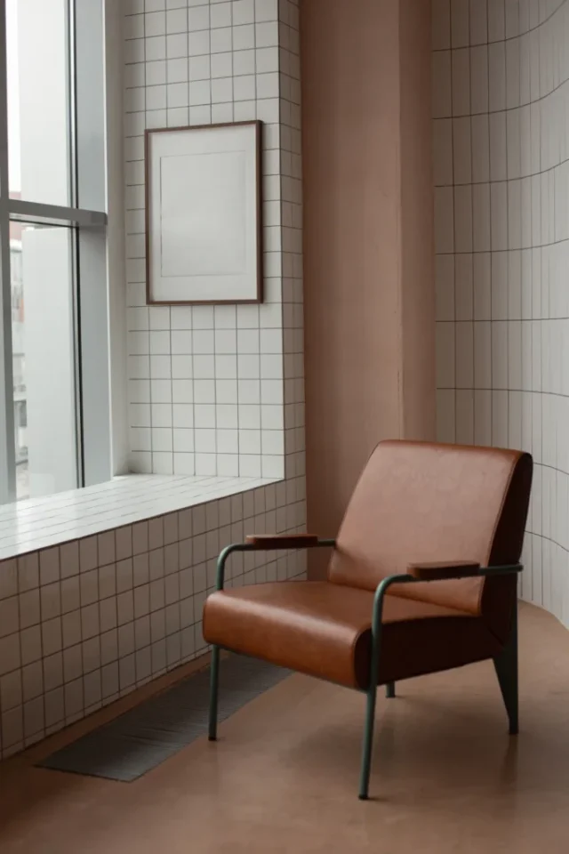 A minimalist room featuring a brown leather armchair and a framed blank canvas, ideal for modern decor inspiration.