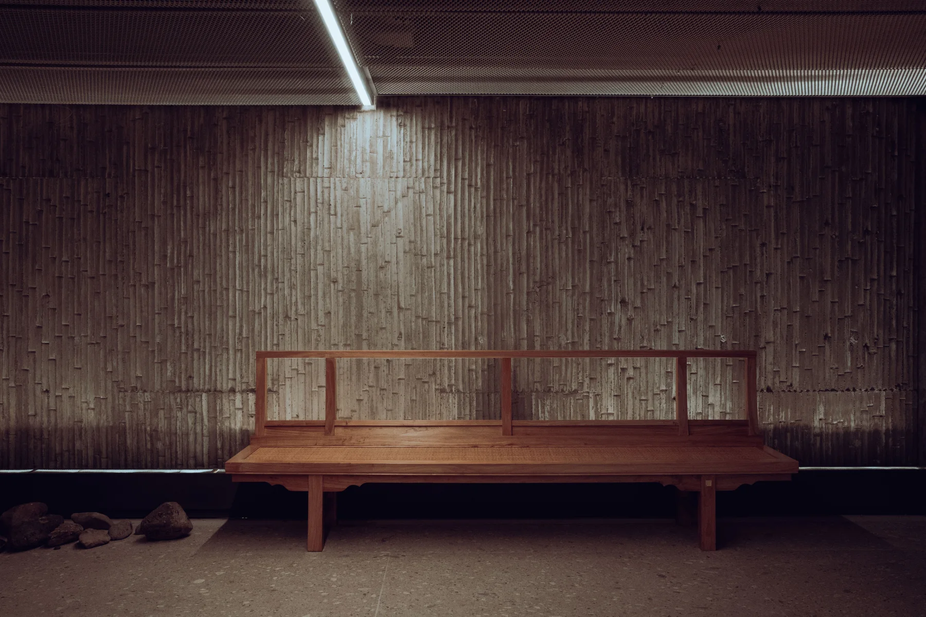 Elegant interior with a bamboo wall and a wooden bench, showcasing contemporary design.